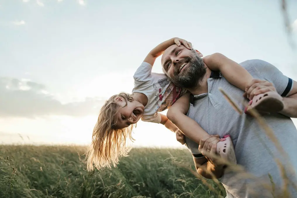 Man with child on his shoulders laughing in nature 