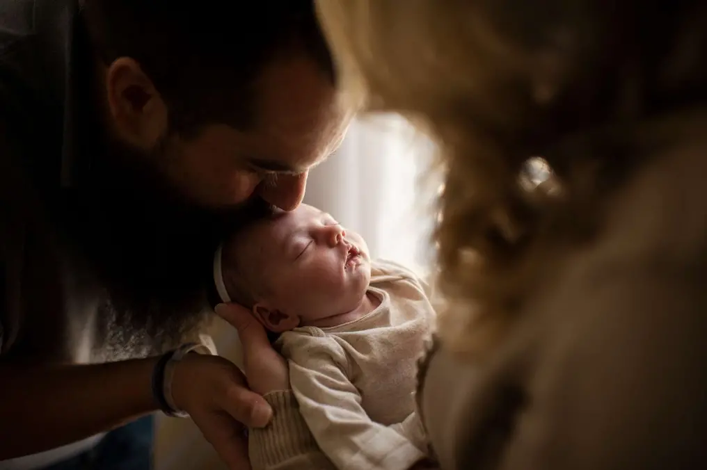 Father kissing a sleeping newborn baby