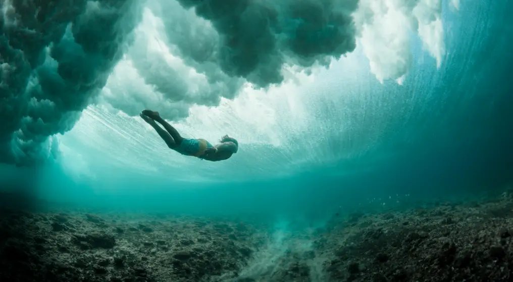 Man swimming under a wave