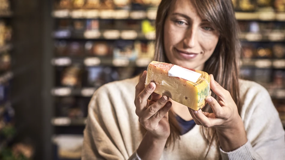 A woman in a supermarket examining a wedge of continental cheese