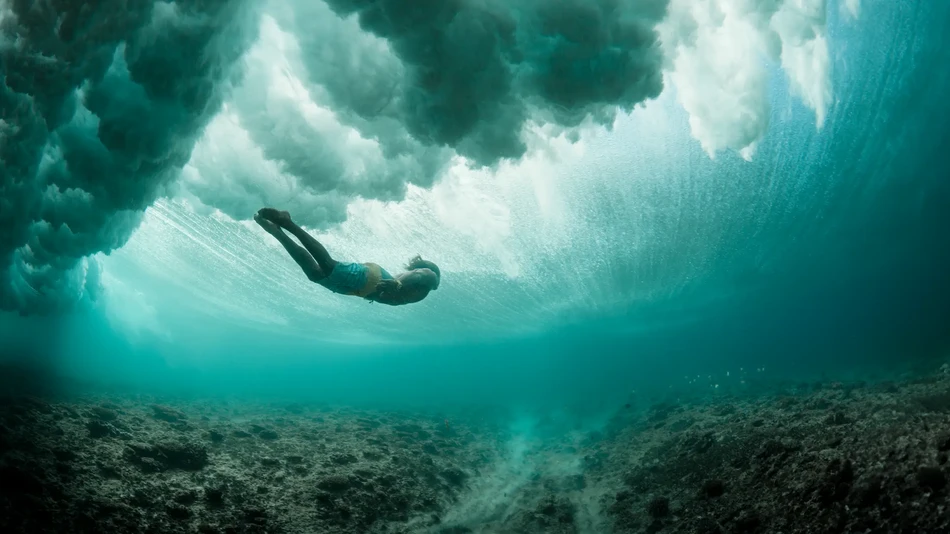 Man swimming under a wave