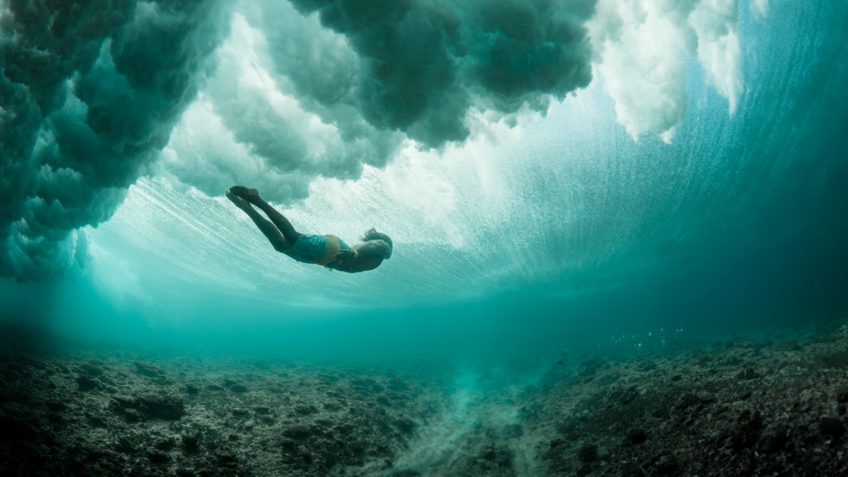 Man swimming under a wave