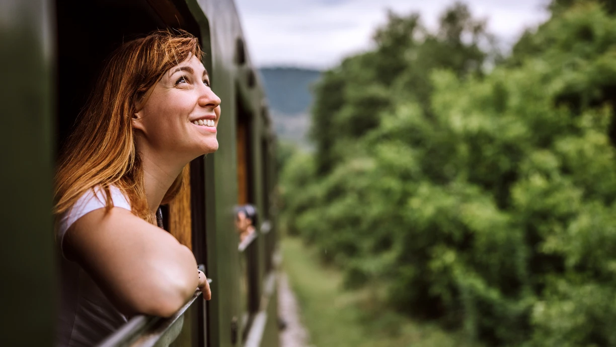 Smiling woman looking out of a window in a train