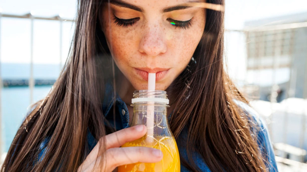 A close up of a woman drinking orange juice