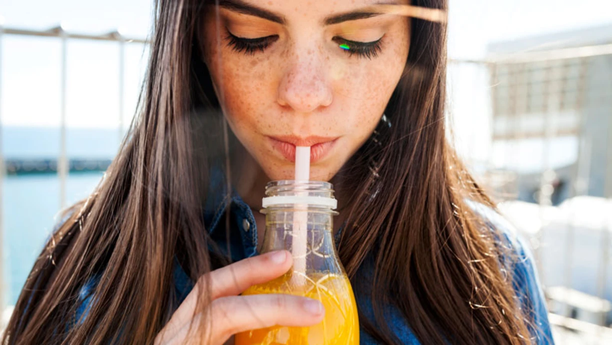 A close up of a woman drinking orange juice