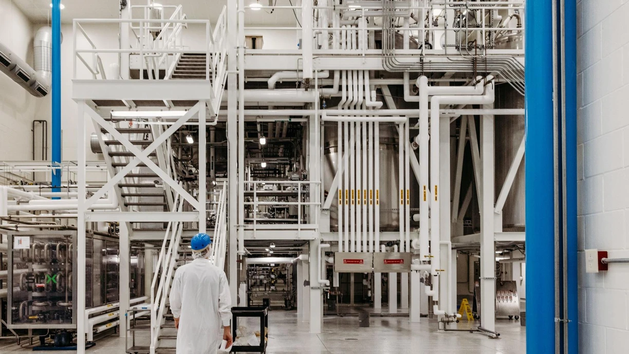 A NVS colleague walks on a manufacturing production floor surrounded by equipment and technology 