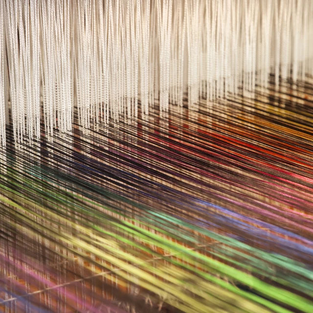 Close up of a loom weaving colorful fabric.