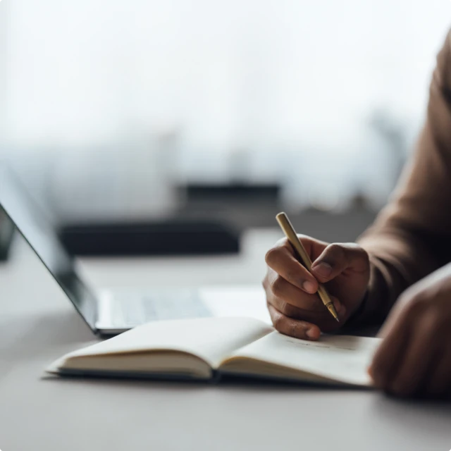 Hand holding pen over a notebook