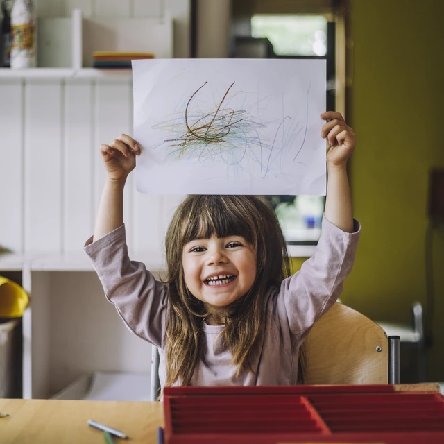 Little girl holding up drawing