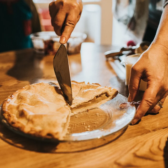 Woman cuts a slice of Warm Apple Pie