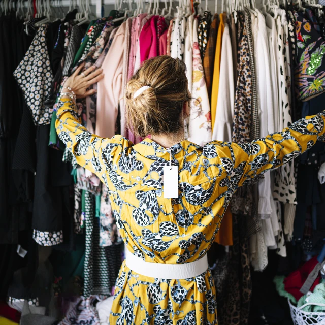 Woman in yellow dress from behind looking at clothes 