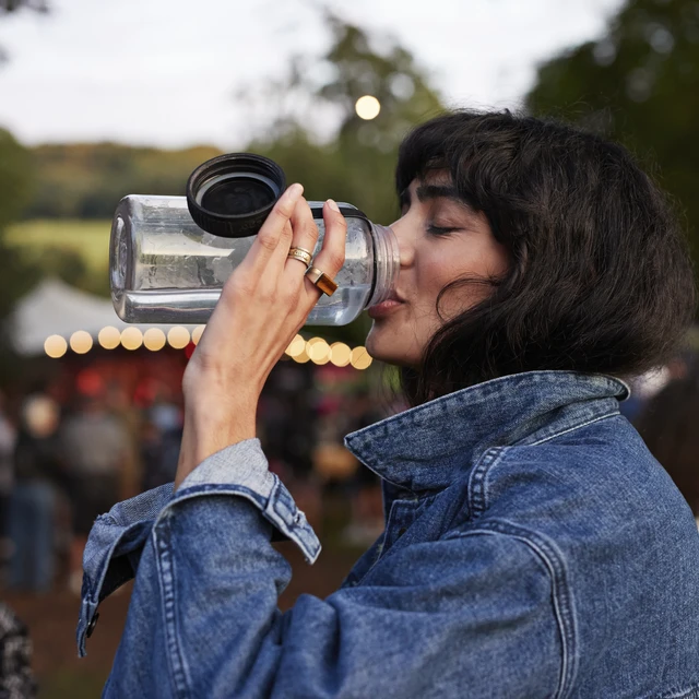 Woman with a denim jacket drinking from water bottle 