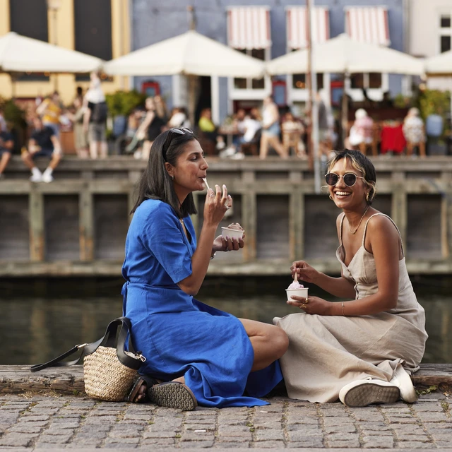 Young women enjoying ice cream on pier.