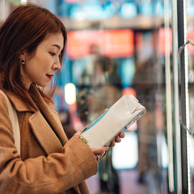 Asian lady looking at labels on plant based drinks
