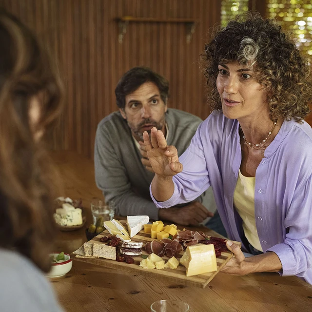 People enjoying a charcuterie board with a number of cheese varieties 