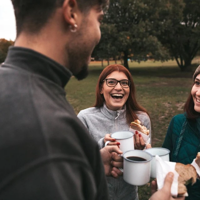 People laughing and eating sandwiches in a park