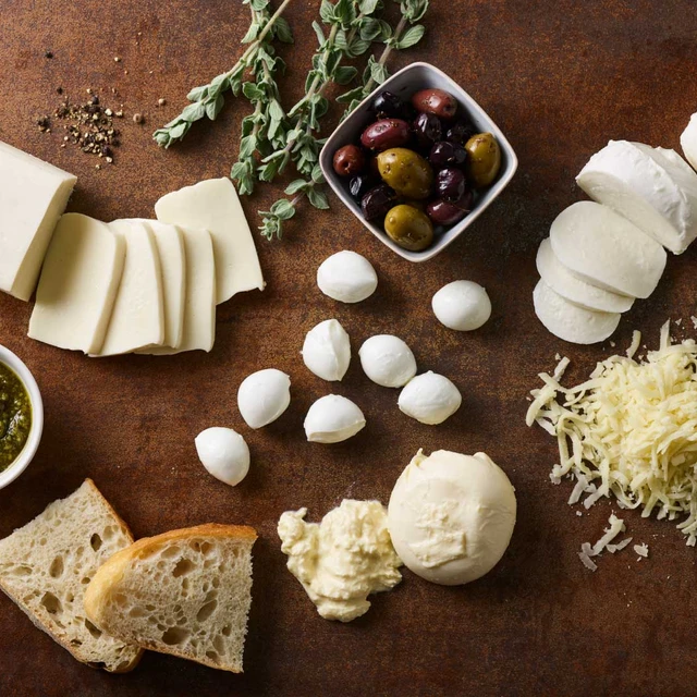 Cheese, olives, bread and herbs on a table spread