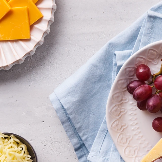 Cheese and grapes on plates on a table with grapes