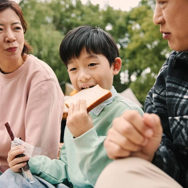 Child eating bread in a park with family
