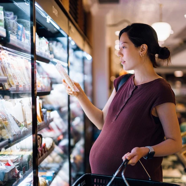Pregnant woman picks up an item at the grocery store 