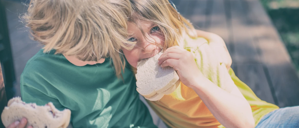 Boy and girl each eating a sandwich 