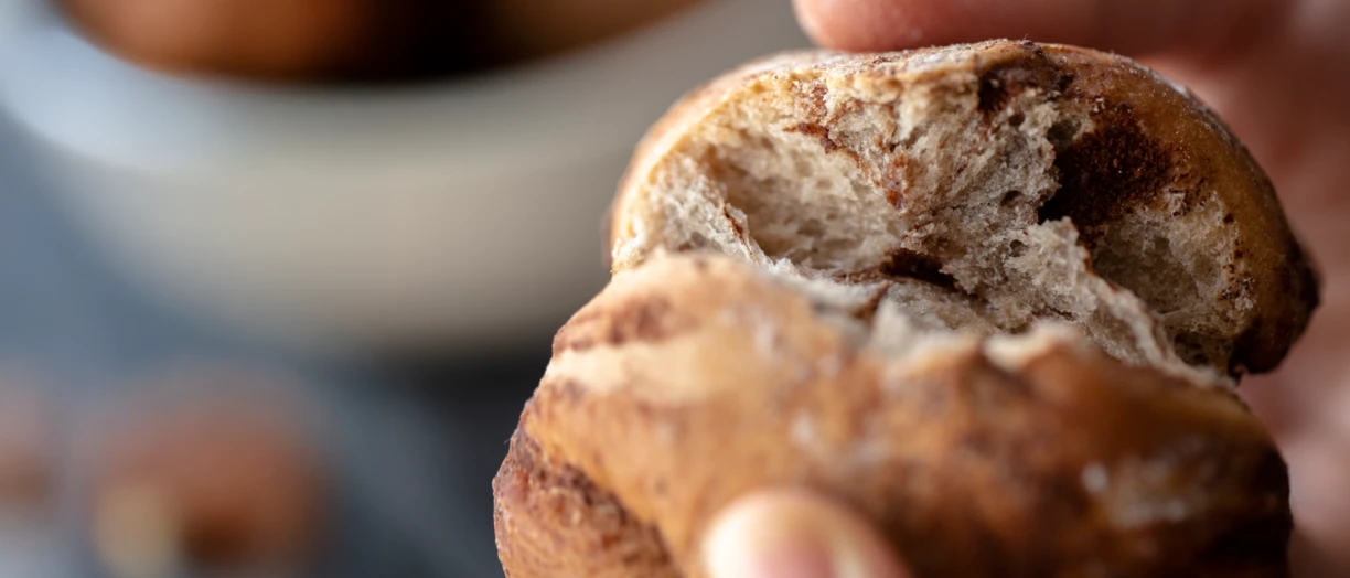 Close up of hands tearing into a cinnamon roll