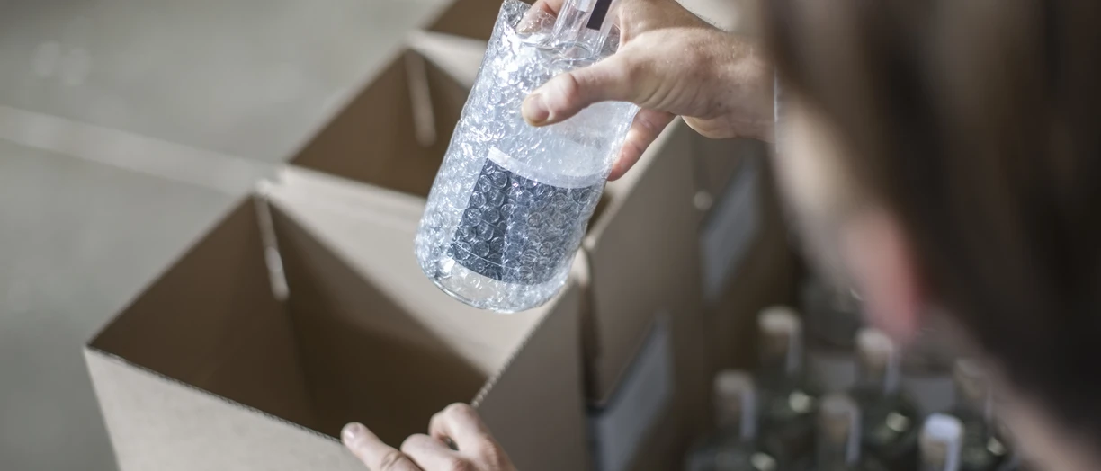 Man putting bottle of liquor into cardboard box