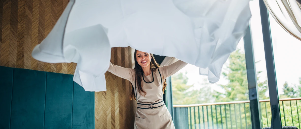 Housekeeper making the bed at a hotel