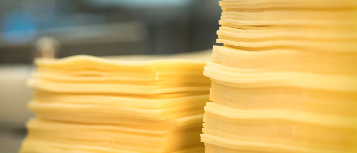 Two stacked piles of thinly sliced cheddar cheese,