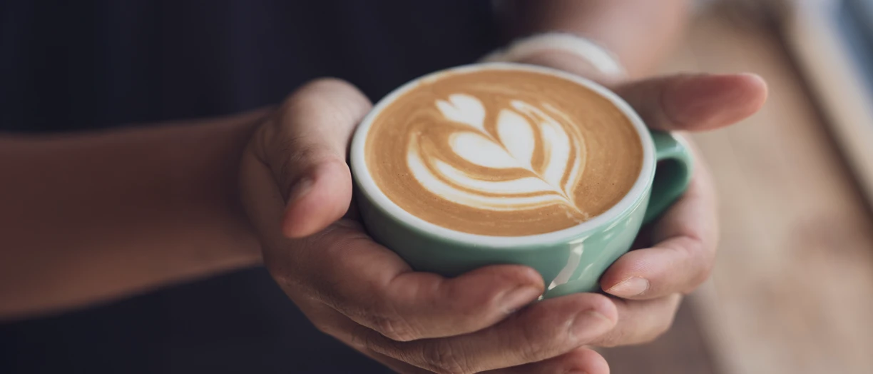 Hands holding cup of hot coffee latte cappuccino