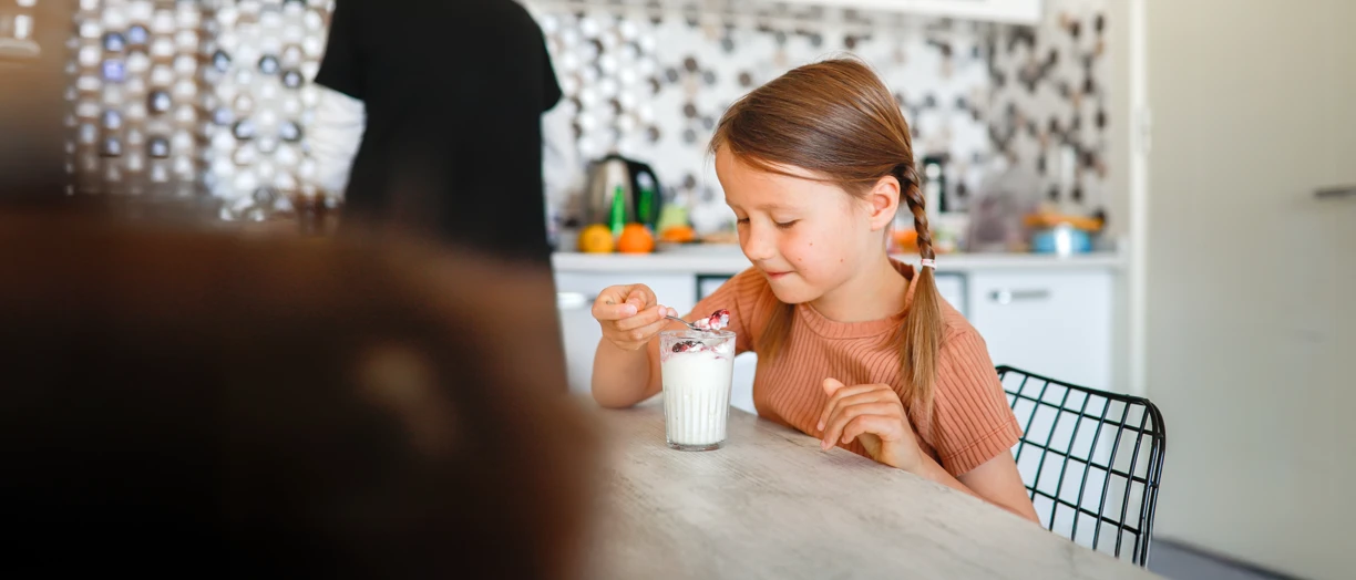 Young female hand eating peach yogurt with spoon.png