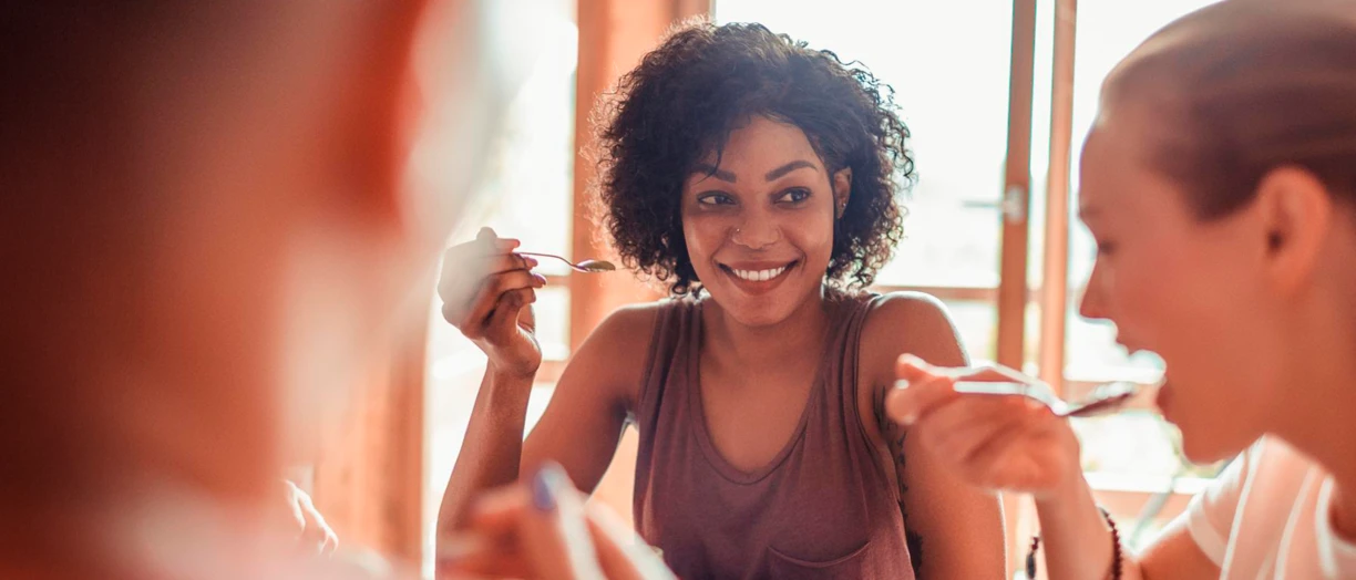 Young female hand eating peach yogurt with spoon.png