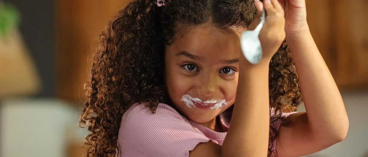 girl licking spoon of yoghurt