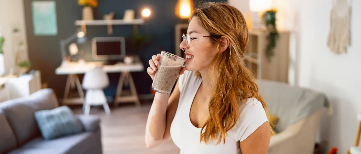 Redhead Caucasian woman with vitiligo, drinking smoothie she made