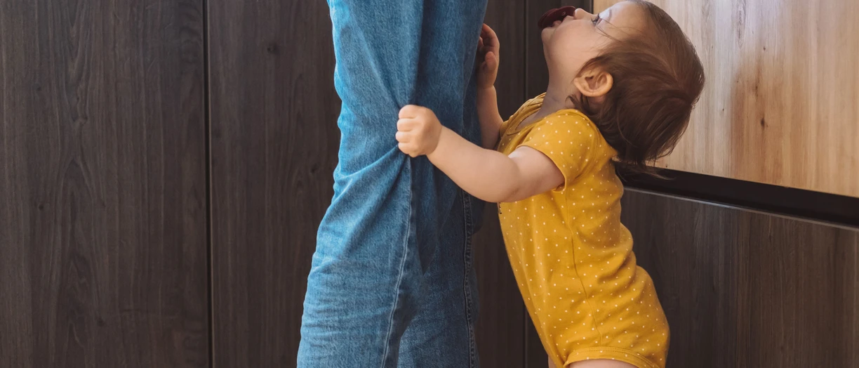 a baby holding an adult's jeans