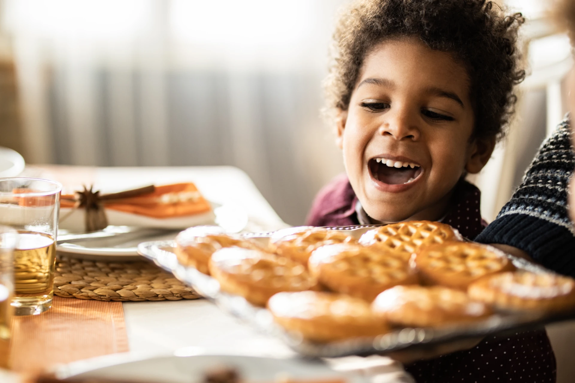 Kid sitting at a table looking at biscuits and cookies 