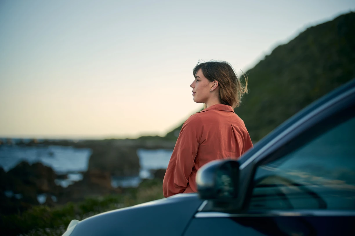 Woman_beside_car_looking_in_the_horizon
