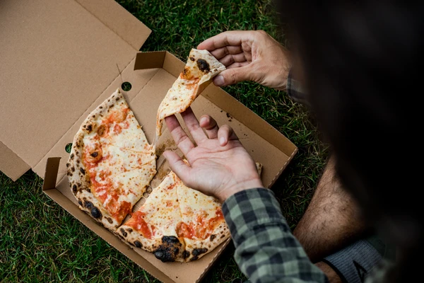 a man eating pizza from a takeaway pizza box