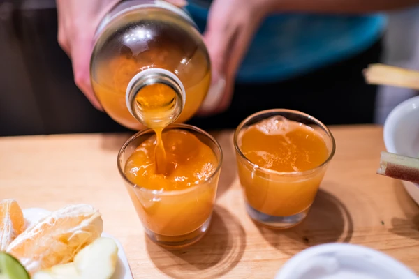 Person serving a glass of kombucha