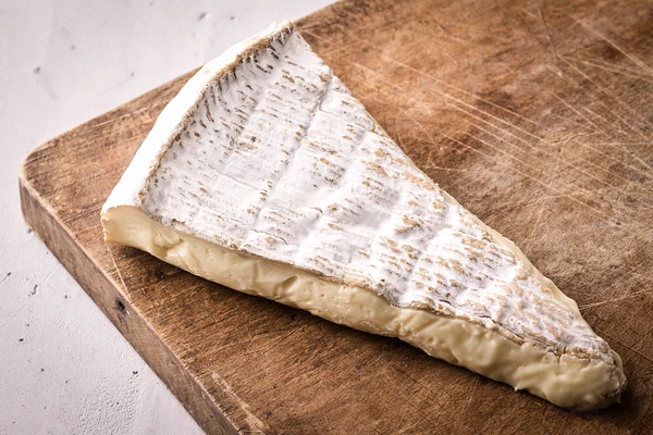 A wedge of Brie on a wooden board 