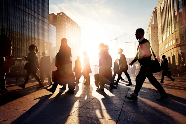 Office workers walking down a city street with the sun setting in the background 