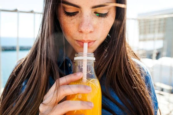 Woman drinking orange juice while looking down