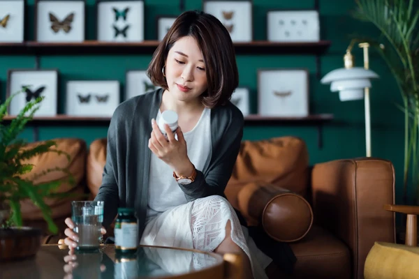 Asian lady looking at bottle of supplements