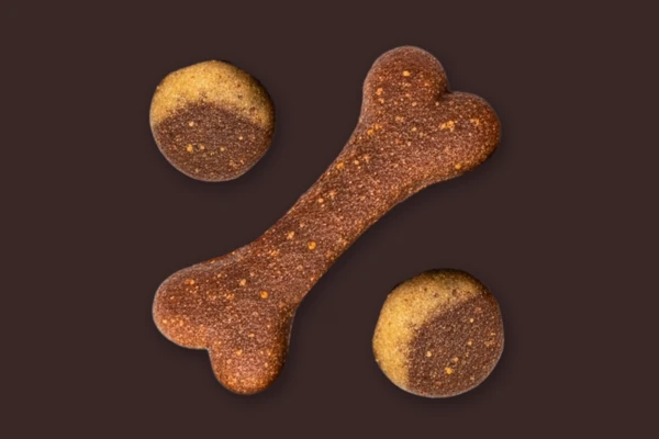 Pet food kibble arranged to represent a percentage symbol on a dark brown background.