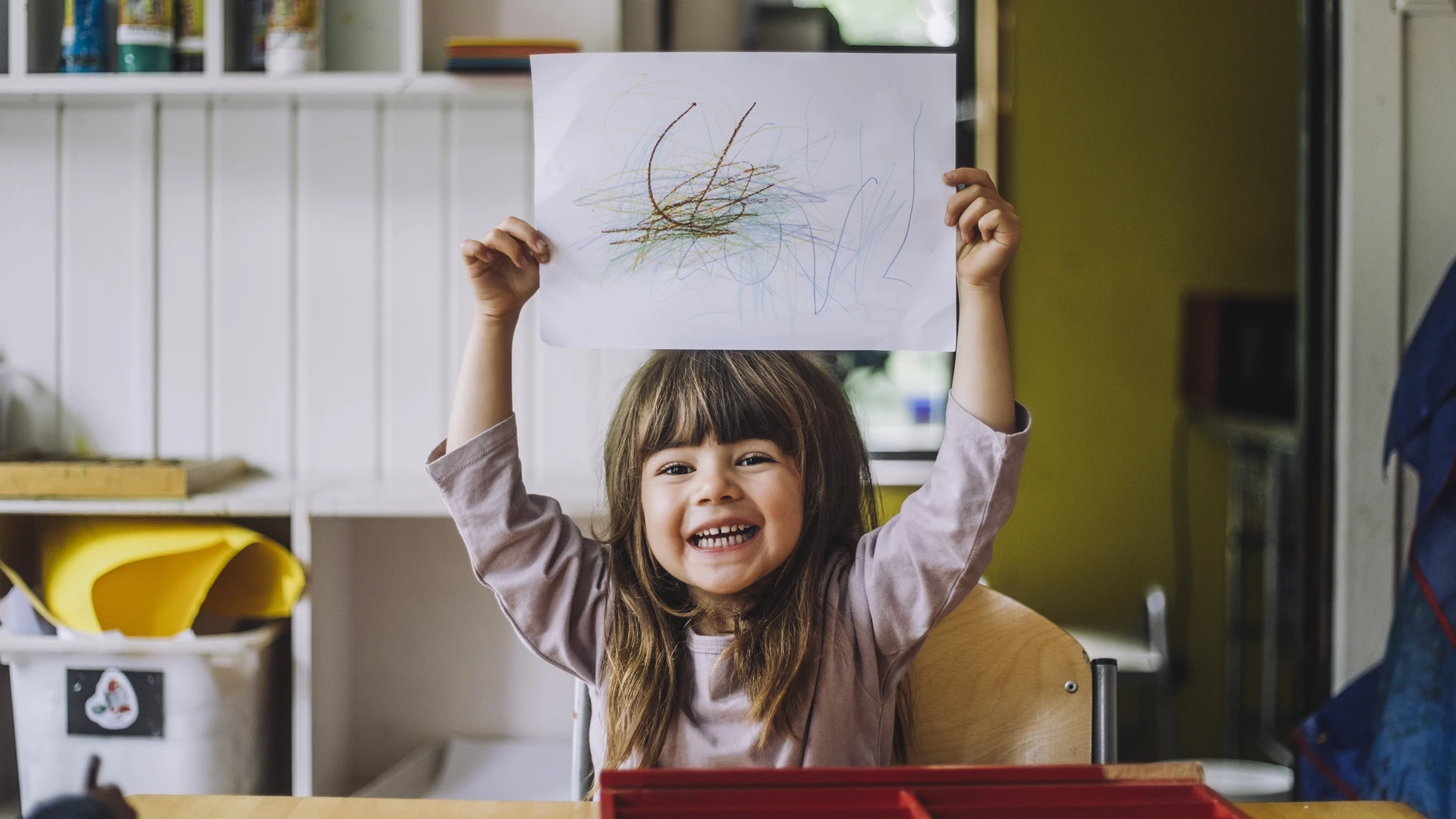 Little girl holding up drawing
