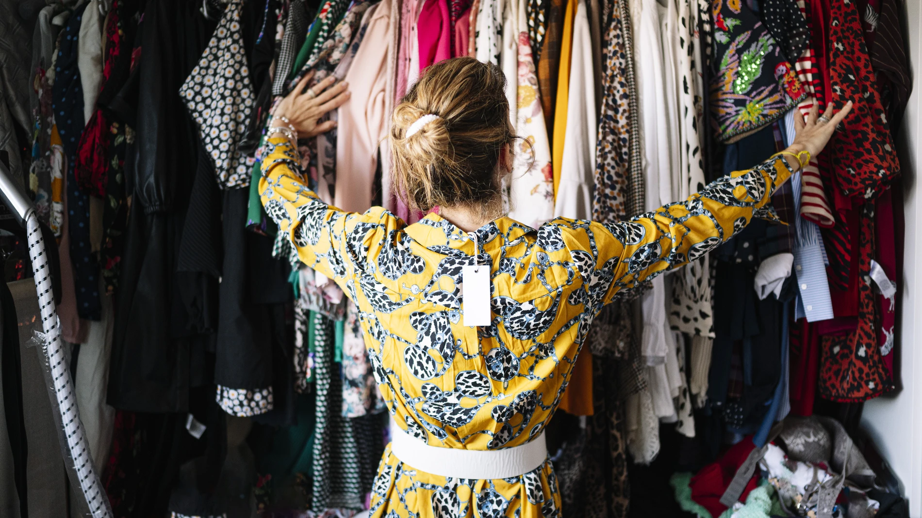 Woman in yellow dress from behind looking at clothes 