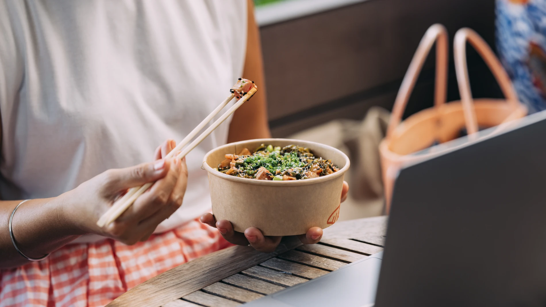 Woman using chopsticks to eat food from disposal box
