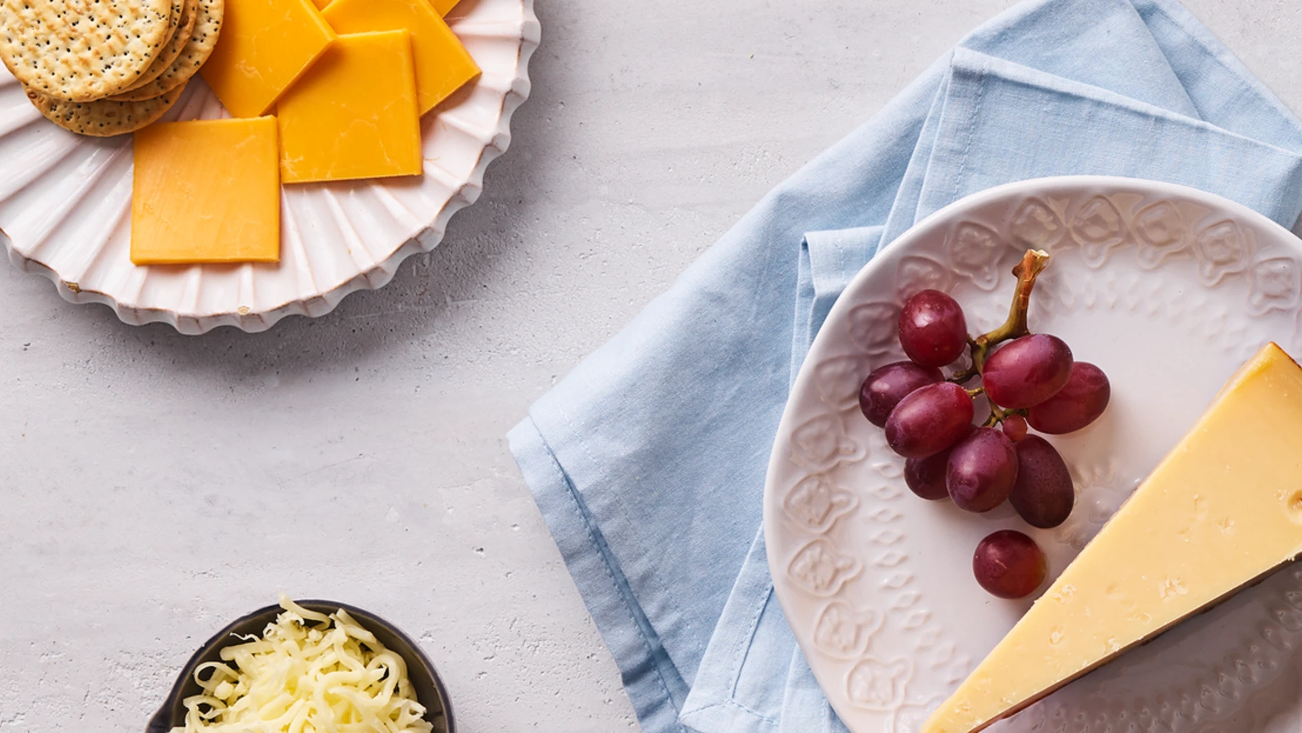 Cheese and grapes on plates on a table with grapes