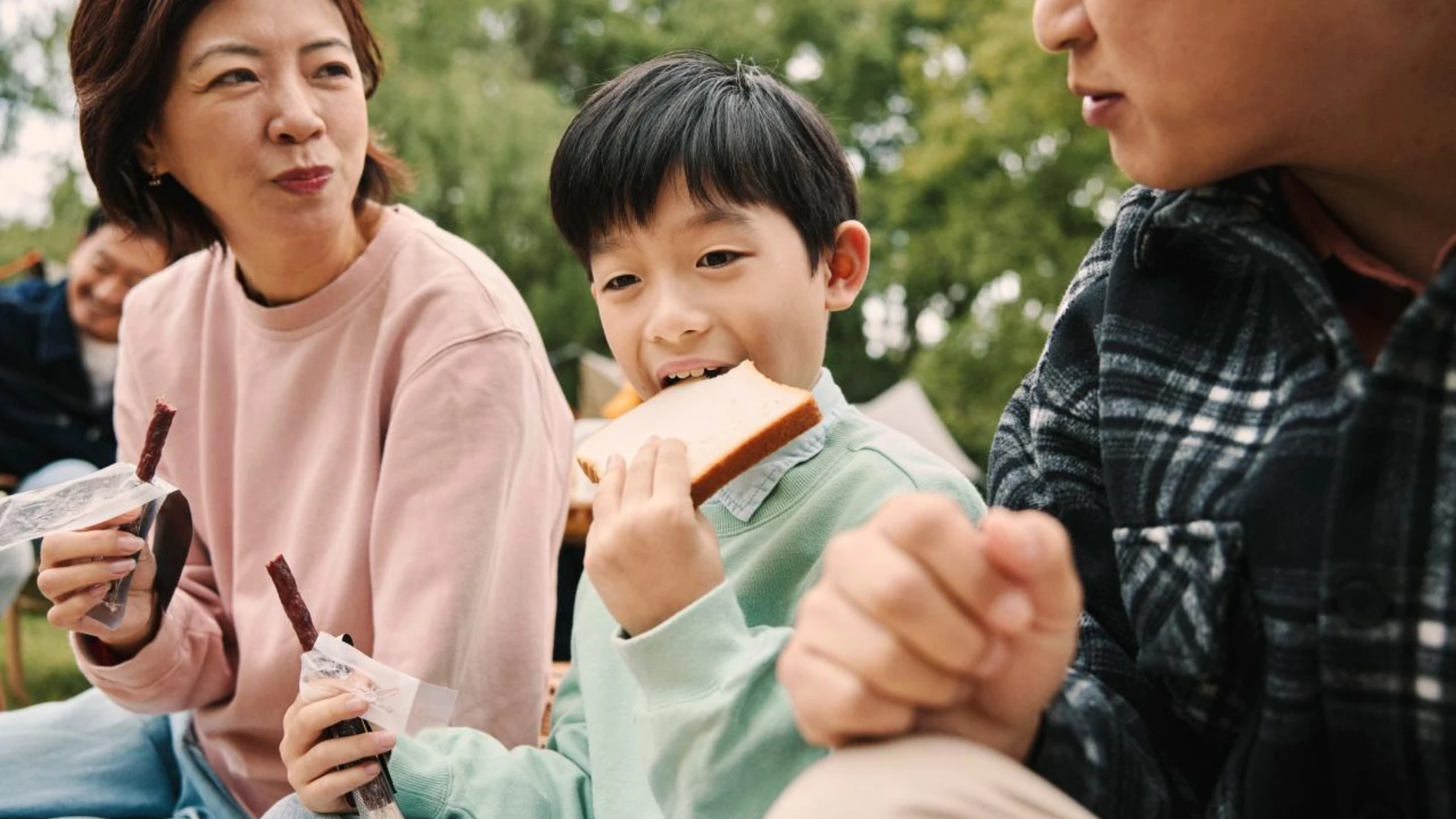 Child eating bread in a park with family
