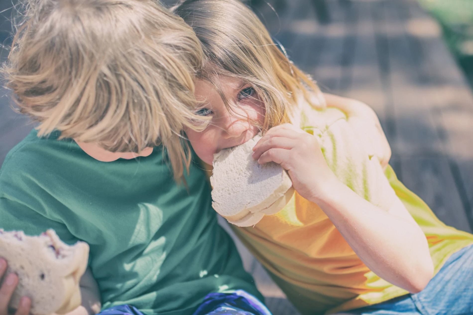 Boy and girl each eating a sandwich 